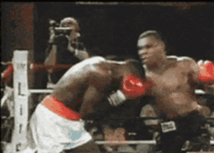 A person in boxing gloves punching another person in a boxing ring